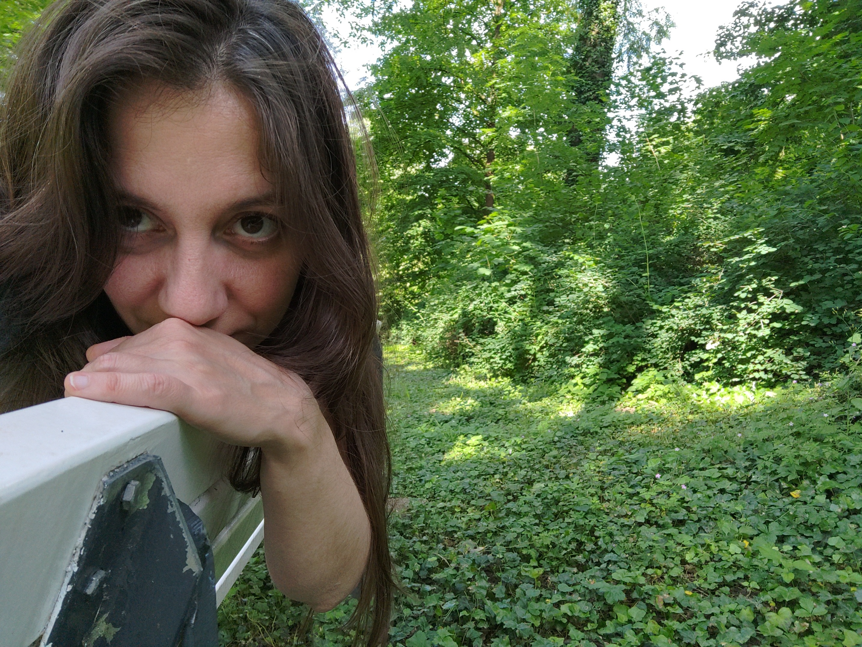 Me sitting on a bench in the park, resting my arm and head on the backrest.